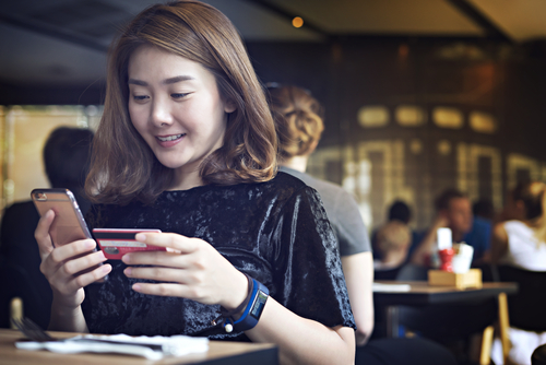 woman_in_cafe_with_credit_card_making_phone_purchase